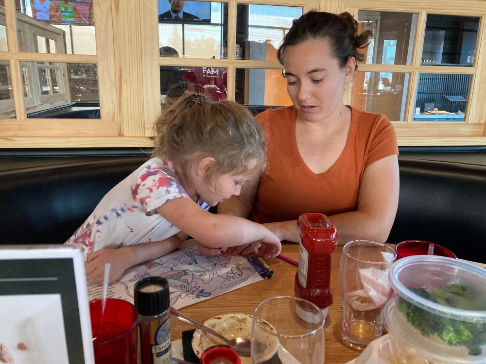 Young woman and young child coloring at a restaurant table